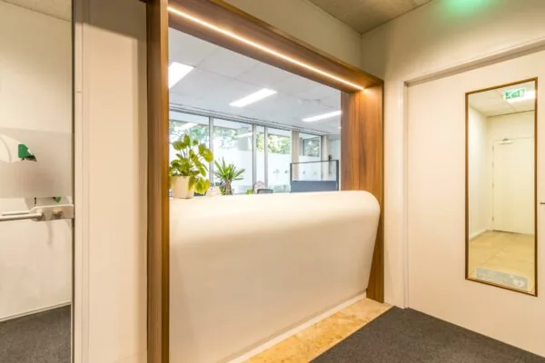 Moderne balie met houten omlijsting en planten in een licht kantoor aan de Jan van Eycklaan.